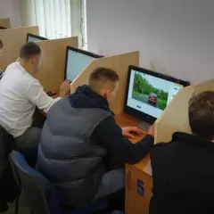 Ludzie siedzą przy komputerach, rozwiązując testy. Tak sprawdzisz, jak zdałeś egzamin teoretyczny na prawo jazdy.