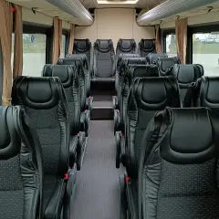 Wnętrze busa 20 osobowego z rzędami czarnych, wygodnych foteli. Idealny na wycieczki i transport grupowy.