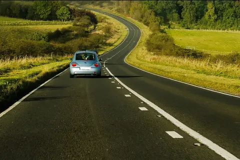 Błękitny Volkswagen Beetle jedzie krętą drogą przez zielone pola. Uważaj na punkty, za ile punktów zabierają prawo jazdy!