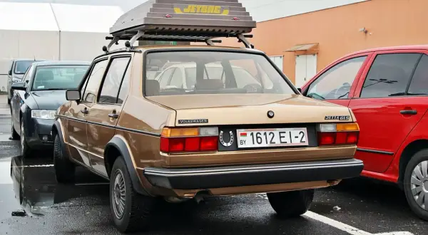 Złoty Volkswagen Jetta GLS z bagażnikiem dachowym Jetbag. Na tablicy rejestracyjnej widnieje oznaczenie BY, co wskazuje na rejestracja kraj.