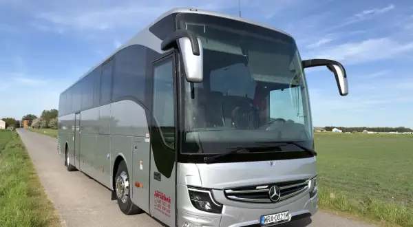 Srebrny autokar na tle błękitnego nieba. Zastanawiasz się, ile miejsc ma autokar? Ten wygląda na przestronny, idealny na wycieczki.