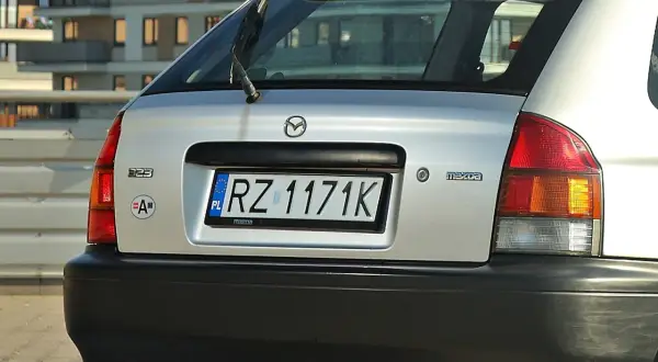 Srebrna Mazda 323 z tablicą rejestracyjną RZ 1171K.