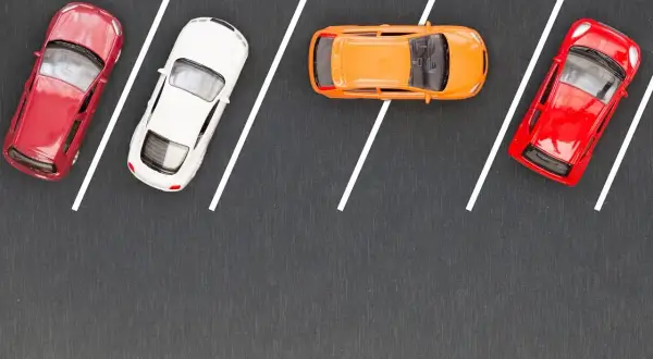 Czerwony, biały i pomarańczowy samochodzik na parkingu. Ucz się, jak parkować równolegle, obserwując te modele.