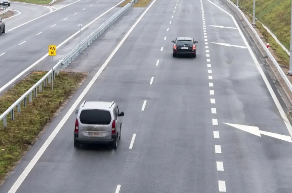 Samochody jadące autostradą. Po lewej stronie widać znak "PA 10" i barierki. Droga ma pas rozbiegowy.
