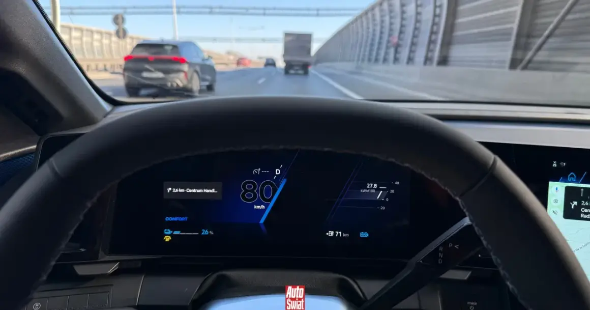 Widok zza kierownicy na autostradzie, prędkość 80 km/h. Na wyświetlaczu widać informację o zasięgu 71 km i trybie jazdy COMFORT. Minimalna prędkość na autostradzie nie jest tu widoczna, ale jazda 80 km/h jest bezpieczna.