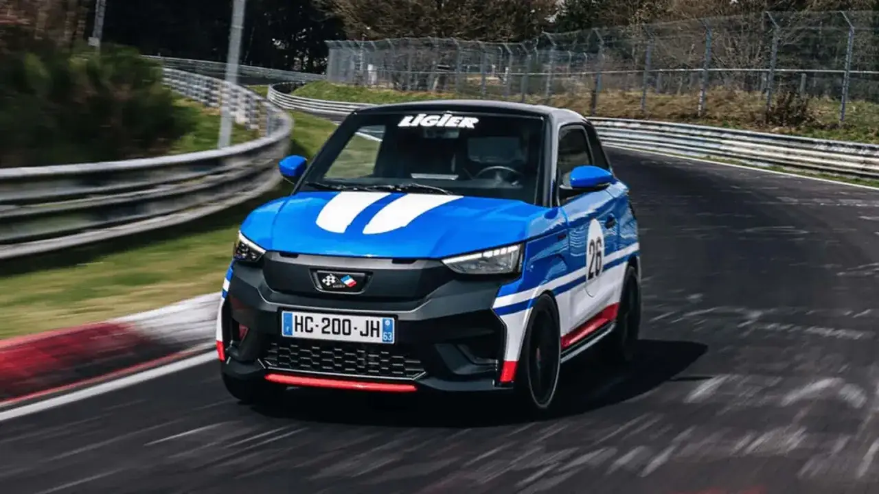 Niebieskie auto Ligier z białymi pasami i numerem 26 na torze wyścigowym. Idealne auto od 16 lat na pierwsze szaleństwa.