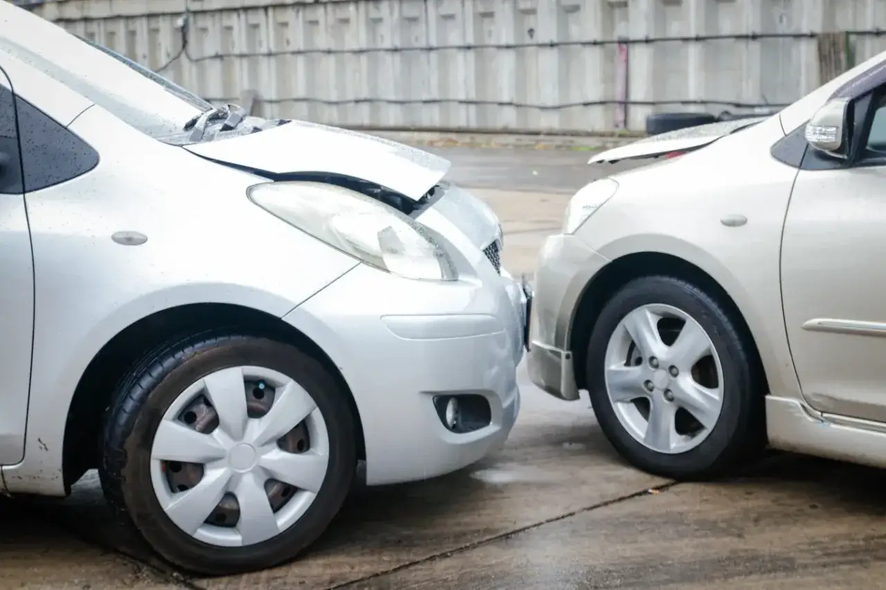 Kolizja na parkingu podczas cofania. Dwa samochody zderzyły się przodem. Sprawcy grozi mandat.