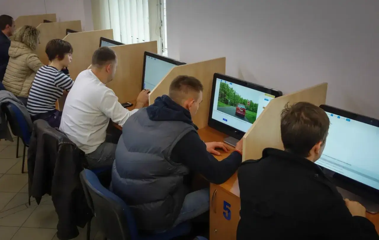 Ludzie siedzą przy komputerach, rozwiązując testy. Zastanawiasz się, ile trwa egzamin teoretyczny na prawo jazdy? Tutaj dowiesz się, jak długo trwa.