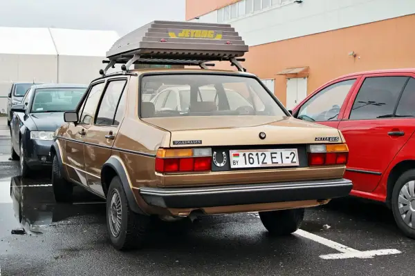 Złoty Volkswagen Jetta GLS z bagażnikiem dachowym Jetbag. Na tablicy rejestracyjnej widnieje oznaczenie BY, co wskazuje na rejestracja kraj.