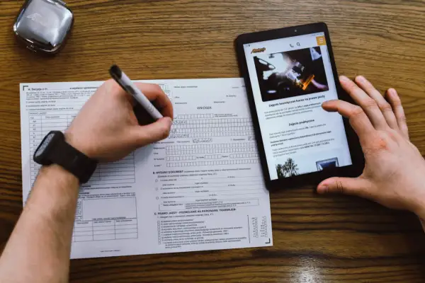 Wypełnianie wniosku o prawo jazdy przez internet. Na zdjęciu widać formularz i tablet z informacjami o kursach.