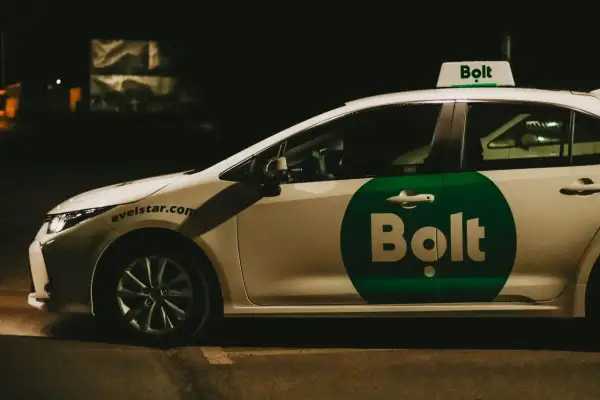 Biały samochód z zielonym logo Bolt na drzwiach i na dachu. To usługa transportowa, co to jest Bolt?