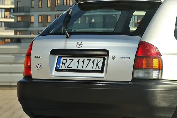 Srebrna Mazda 323 z tablicą rejestracyjną RZ 1171K.