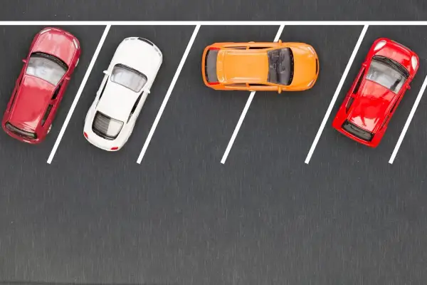Czerwony, biały i pomarańczowy samochodzik na parkingu. Ucz się, jak parkować równolegle, obserwując te modele.