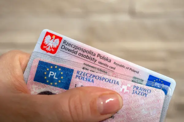 Dłoń trzyma polski dowód osobisty i prawo jazdy. Ważność prawa jazdy jest kluczowa dla swobodnego poruszania się po drogach.