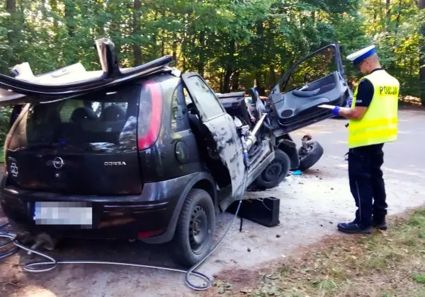 Policjant spisuje raport przy wraku Opla Corsy po wypadku. Czy to rejestracja GKS jakie miasto?